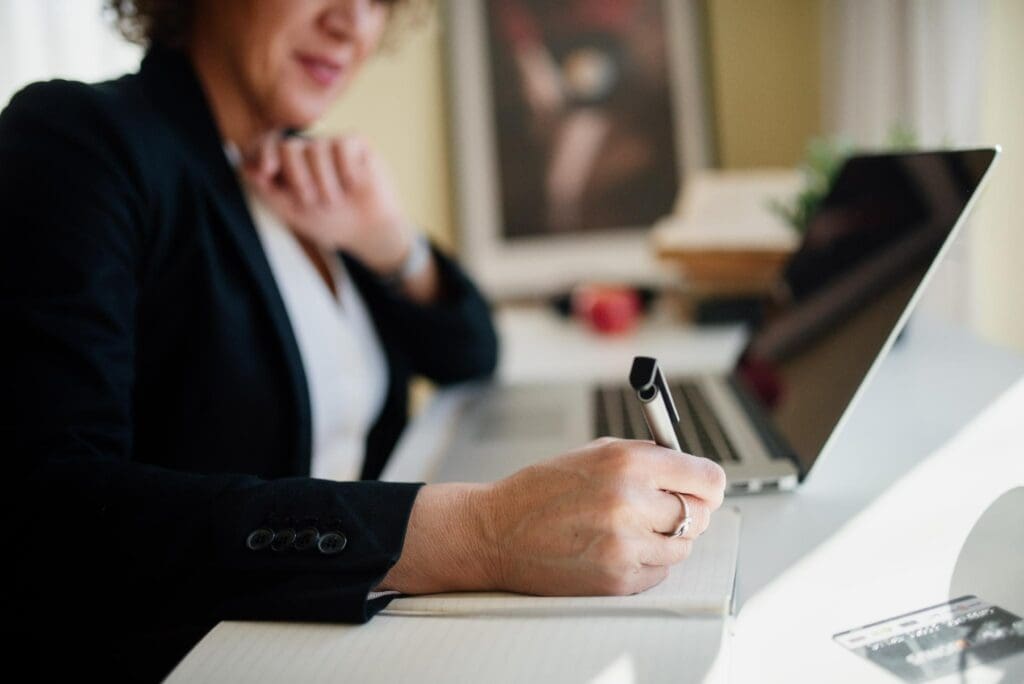 Profissional faz anotações ao lado de um notebook durante uma análise de negócios. A escolha entre o Simples puro e o híbrido deve combinar dados fiscais, preços e perfil dos clientes B2B.